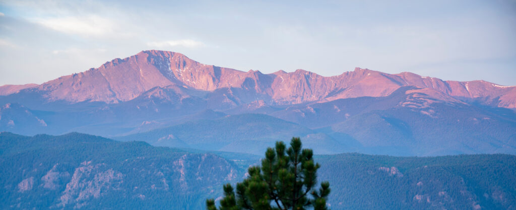 A view of Pikes Peak with an early morning sunrise illuminating it.